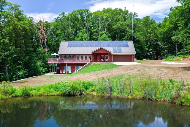 rear view of property featuring a water view and solar panels