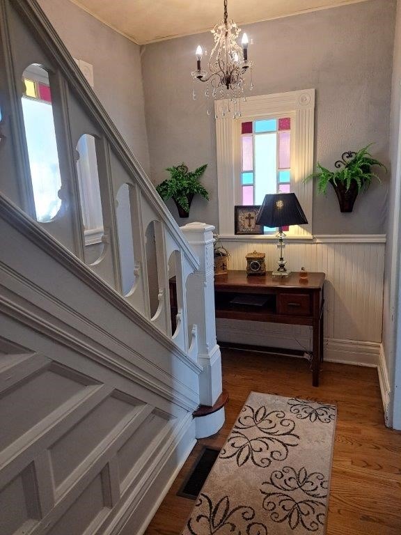 stairs with wood-type flooring and an inviting chandelier