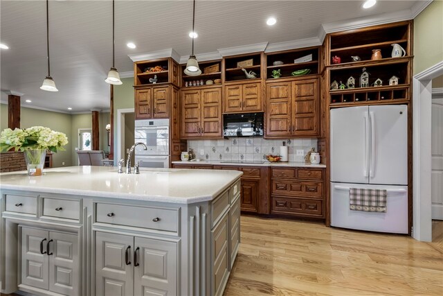 kitchen featuring tasteful backsplash, a kitchen island with sink, black appliances, and decorative light fixtures