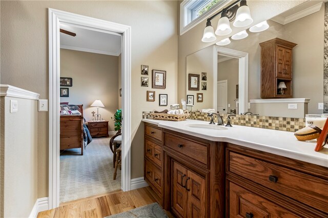 bathroom featuring decorative backsplash, vanity, crown molding, wood-type flooring, and a notable chandelier