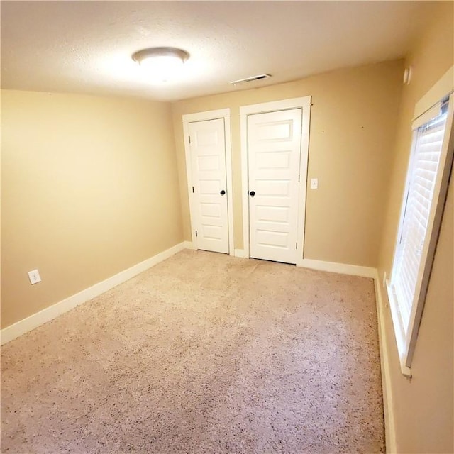 unfurnished room with light colored carpet, visible vents, and baseboards