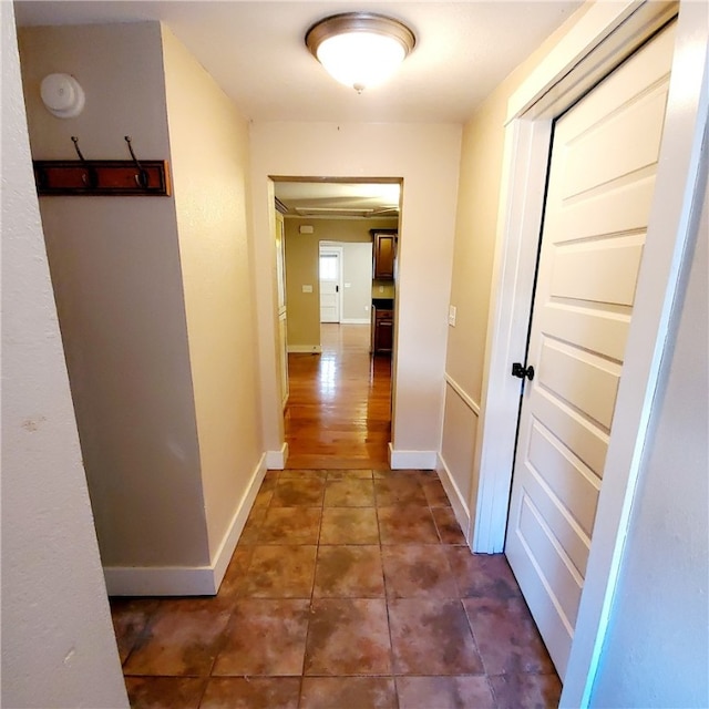 hall featuring dark tile patterned flooring and baseboards