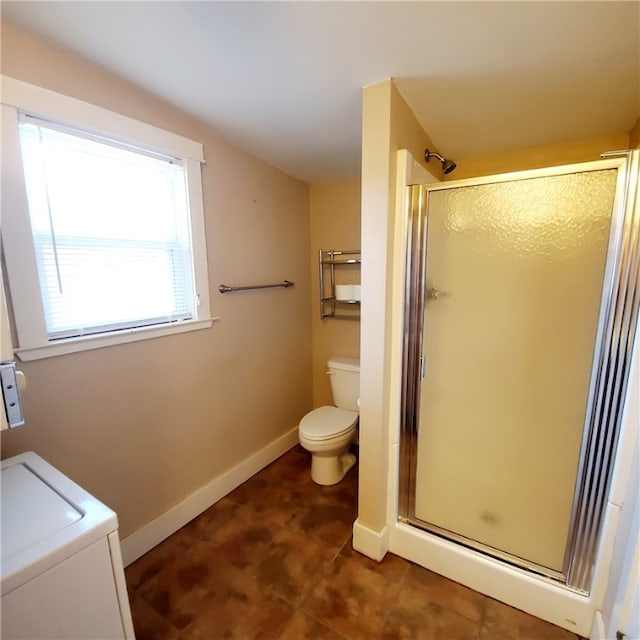 full bathroom with toilet, a stall shower, baseboards, and washer / dryer