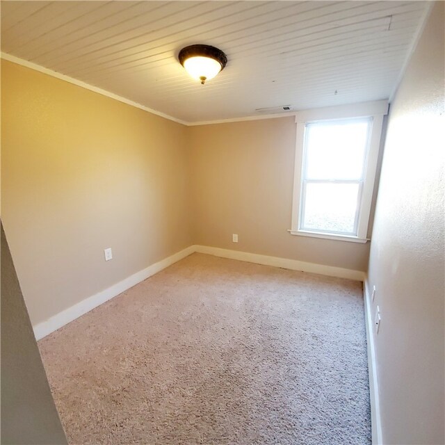 empty room featuring visible vents, baseboards, ornamental molding, and light colored carpet