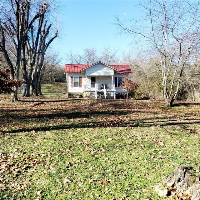 view of front of property featuring a porch, metal roof, and a front lawn