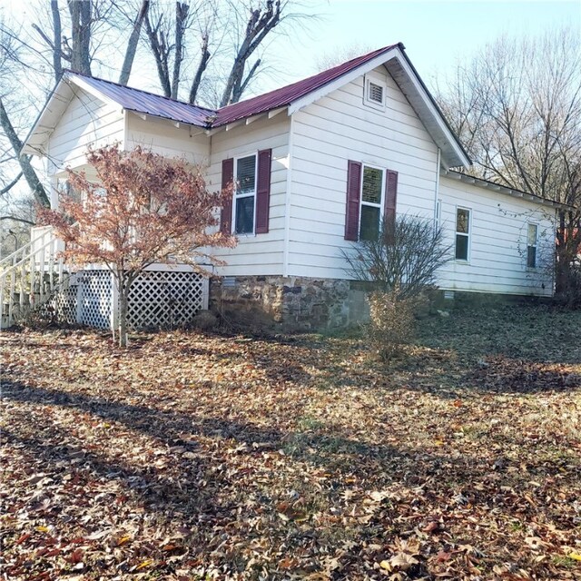 view of side of property with metal roof and crawl space