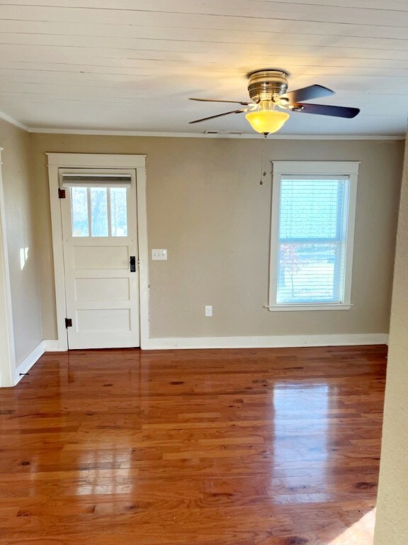 interior space featuring baseboards, ornamental molding, and wood finished floors