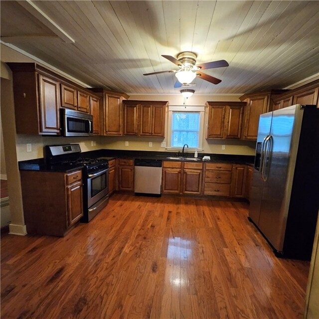 kitchen with dark wood finished floors, dark countertops, wooden ceiling, stainless steel appliances, and a sink