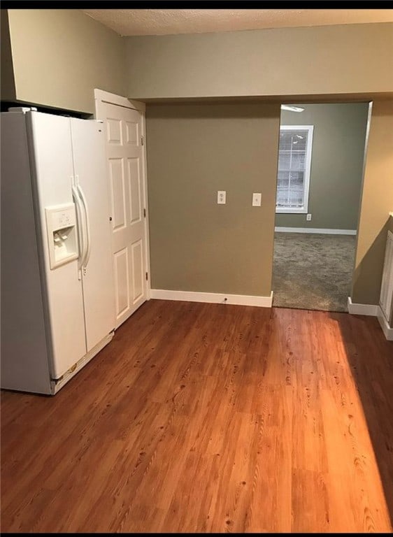 interior space featuring a textured ceiling, wood finished floors, and baseboards