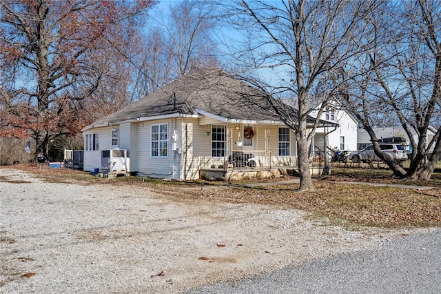 view of front facade with dirt driveway and roof with shingles