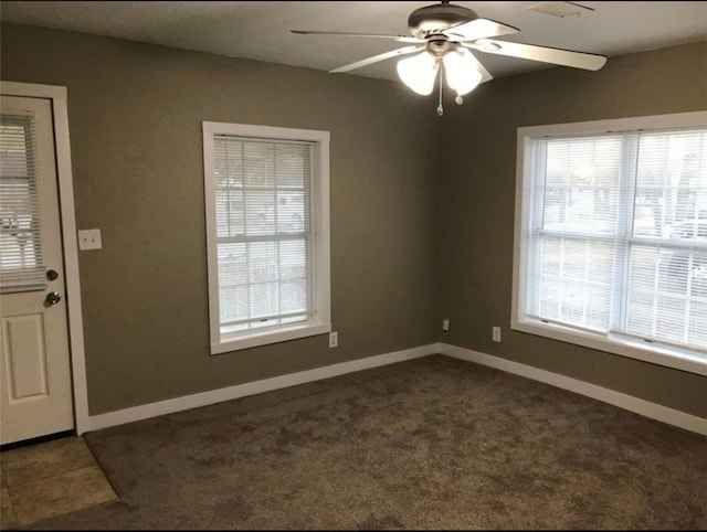 spare room featuring dark tile patterned flooring, dark carpet, a ceiling fan, and baseboards