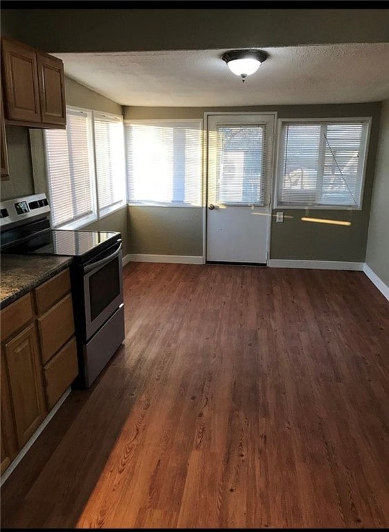 kitchen featuring dark wood-style flooring, brown cabinets, stainless steel range with electric cooktop, a textured ceiling, and baseboards