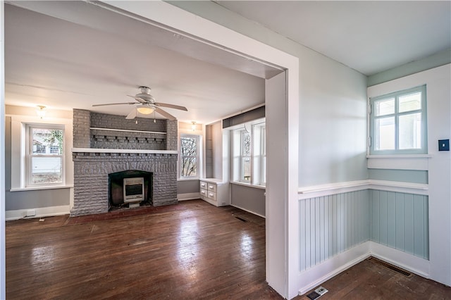 unfurnished living room with a fireplace, dark wood-type flooring, and ceiling fan