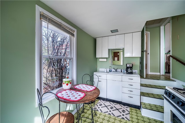 kitchen featuring white cabinets, sink, and white gas stove