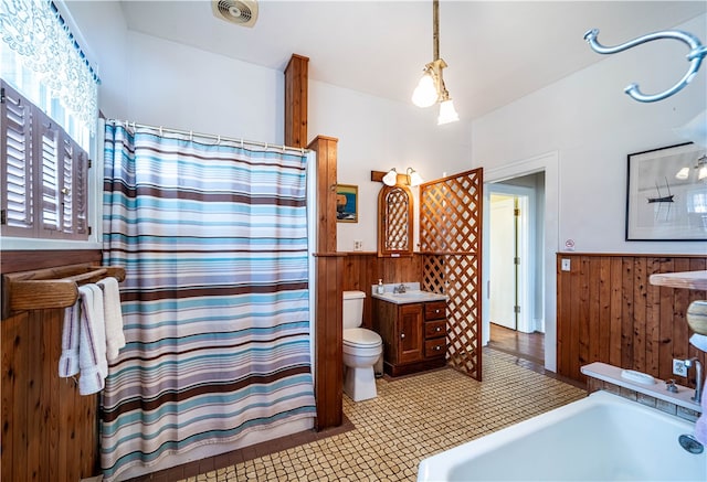 bathroom featuring vanity, wood walls, toilet, and tile patterned flooring