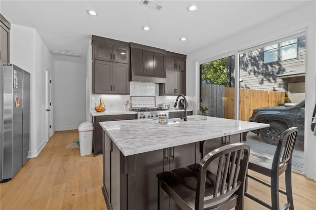 kitchen featuring custom range hood, tasteful backsplash, stainless steel refrigerator, light hardwood / wood-style flooring, and light stone countertops