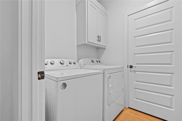 laundry area with washing machine and dryer, cabinets, and light hardwood / wood-style floors