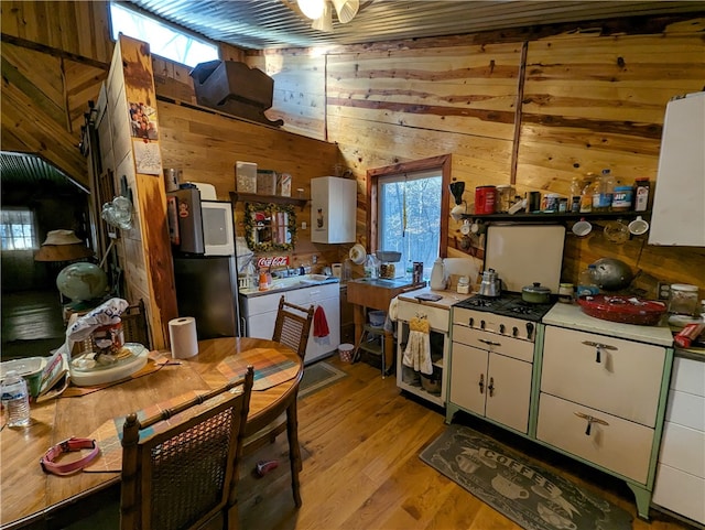 kitchen with white cabinets, wood walls, and light hardwood / wood-style flooring