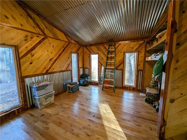 interior space featuring wood walls, lofted ceiling, and light hardwood / wood-style floors