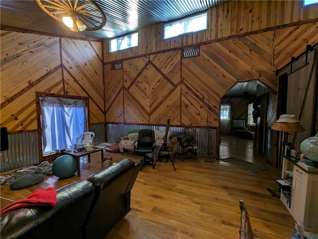 living room featuring a barn door, wooden walls, and light hardwood / wood-style floors