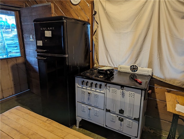 interior space with double oven range, black fridge, and wooden walls