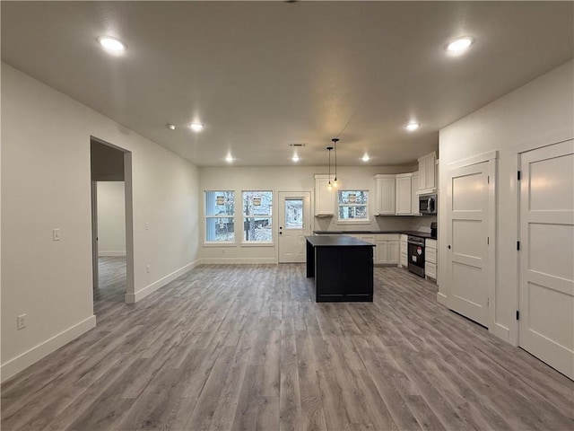 kitchen with light hardwood / wood-style flooring, white cabinetry, hanging light fixtures, stainless steel appliances, and a center island