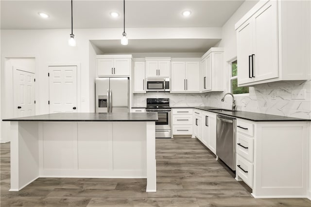 kitchen with pendant lighting, appliances with stainless steel finishes, white cabinets, dark hardwood / wood-style floors, and sink