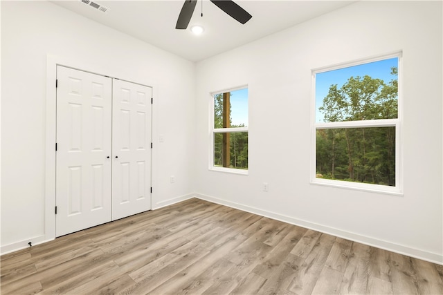 unfurnished bedroom featuring ceiling fan, a closet, and light wood-type flooring