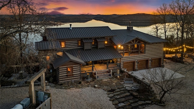 back house at dusk with a garage and a water view