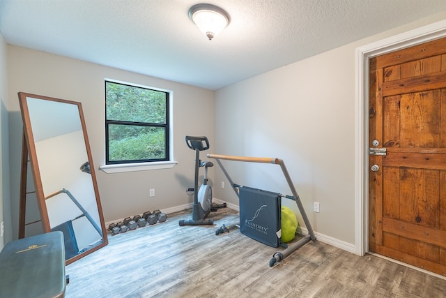 exercise area with a textured ceiling and light wood-type flooring