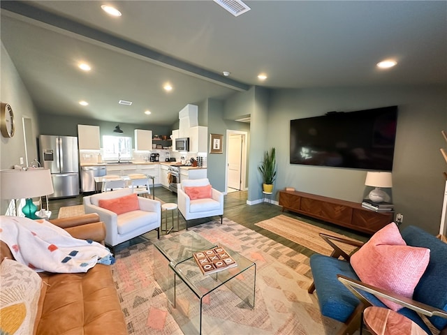 living room with lofted ceiling with beams, light hardwood / wood-style flooring, and sink