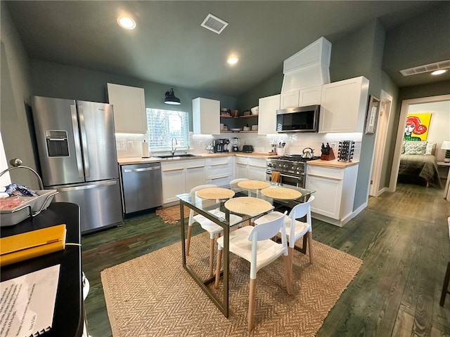 kitchen featuring tasteful backsplash, lofted ceiling, stainless steel appliances, dark hardwood / wood-style flooring, and white cabinets