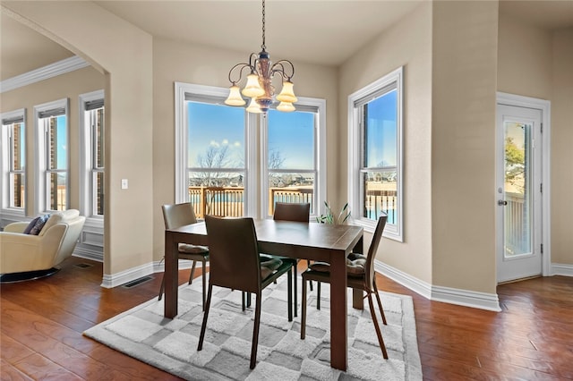 dining area featuring crown molding, dark hardwood / wood-style floors, and a chandelier