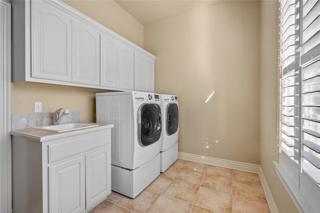 clothes washing area featuring light tile flooring, washing machine and dryer, cabinets, and sink