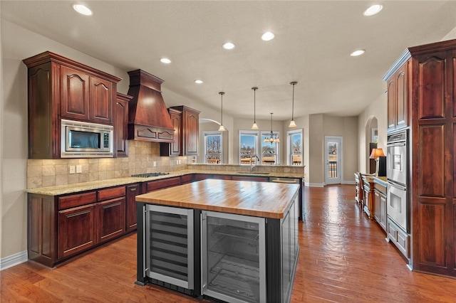 kitchen with wood counters, dark hardwood / wood-style flooring, stainless steel appliances, and custom exhaust hood