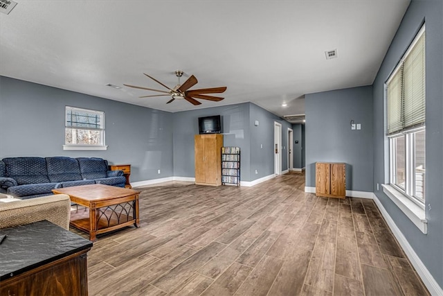 living room with a wealth of natural light, wood-type flooring, and ceiling fan