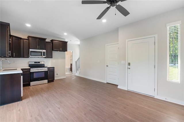 kitchen with dark brown cabinetry, tasteful backsplash, appliances with stainless steel finishes, light countertops, and light wood-type flooring