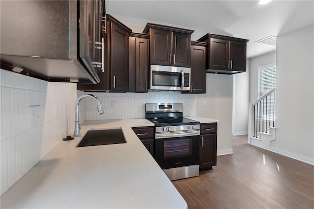 kitchen with a sink, dark brown cabinets, stainless steel appliances, and light countertops