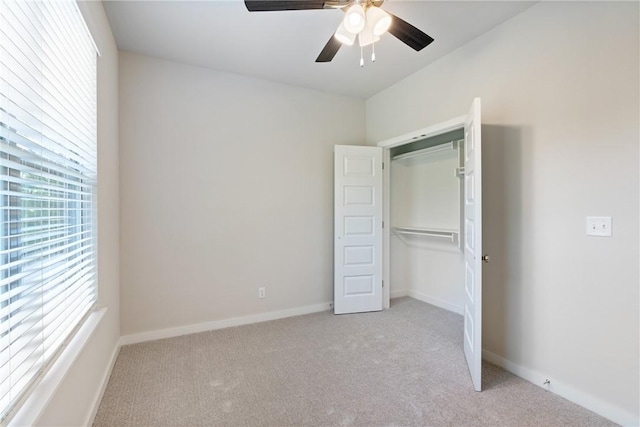 unfurnished bedroom with baseboards, ceiling fan, a closet, and light colored carpet