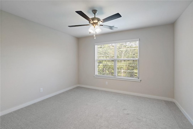 carpeted spare room with ceiling fan and baseboards