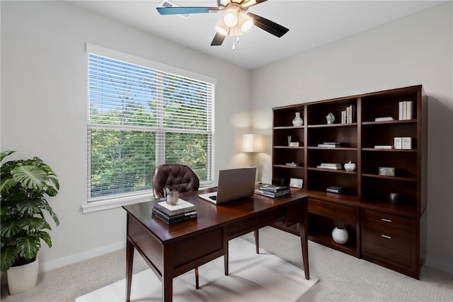 office space featuring light colored carpet, a ceiling fan, and baseboards