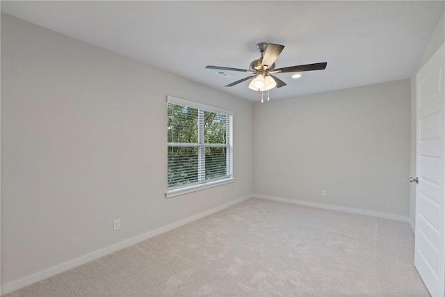 spare room featuring baseboards, a ceiling fan, and light colored carpet