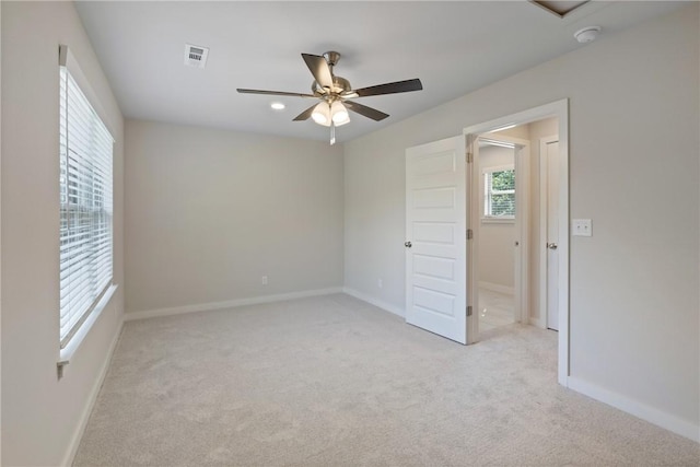 empty room featuring light colored carpet, visible vents, ceiling fan, and baseboards