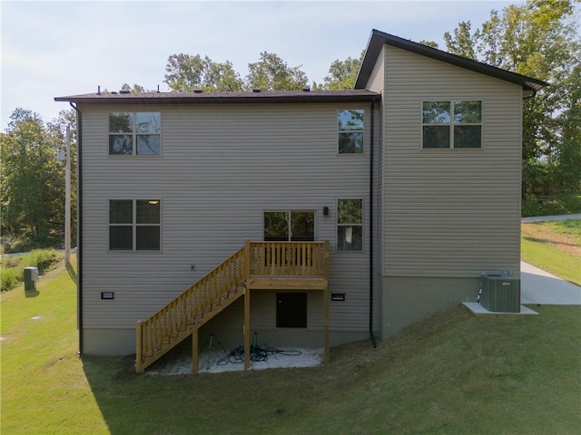 back of property with central AC unit, stairway, and a lawn