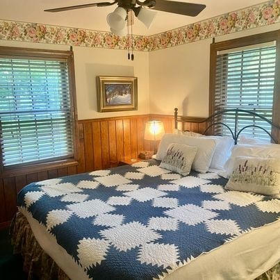 bedroom with ceiling fan and wooden walls