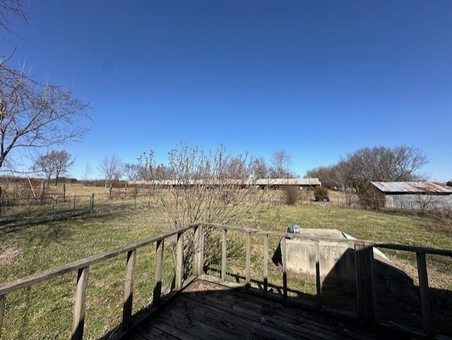 wooden terrace with a rural view and a yard