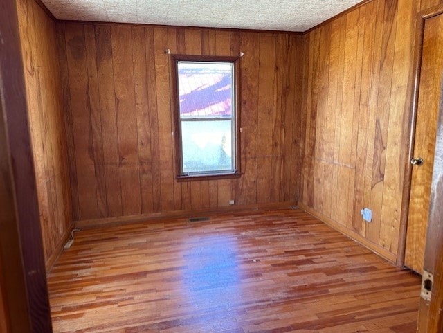 spare room with wood walls and wood-type flooring