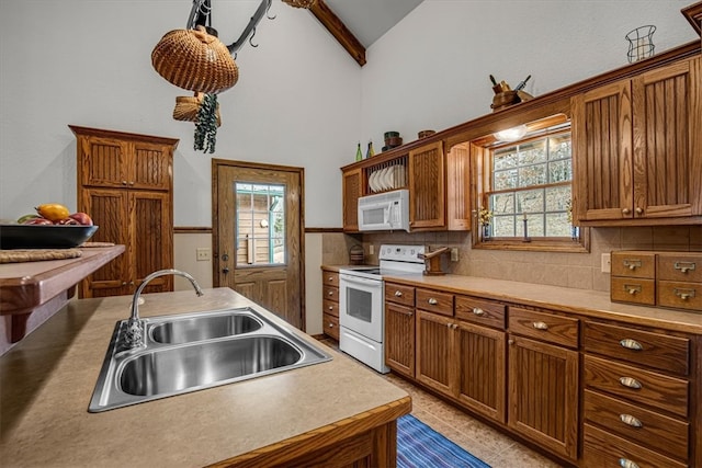 kitchen featuring white appliances, lofted ceiling with beams, plenty of natural light, and sink