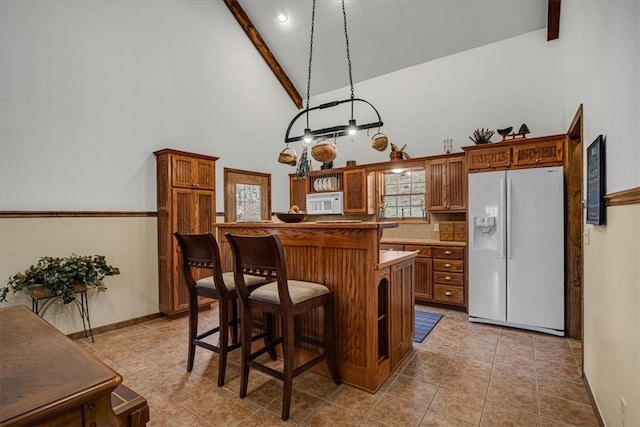 kitchen with white appliances, high vaulted ceiling, hanging light fixtures, light tile patterned floors, and beamed ceiling