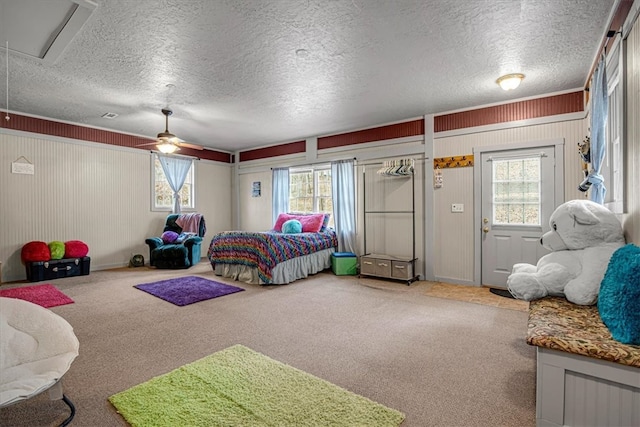 carpeted bedroom with a textured ceiling, multiple windows, and ceiling fan